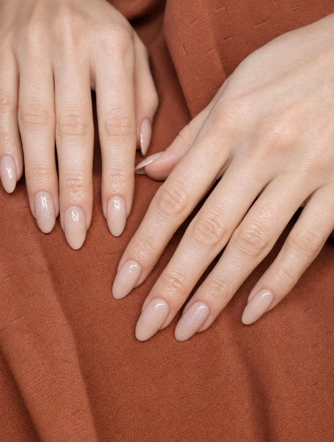 Dłonie z manicure hybrydowym w odcieniu nude, paznokcie w kształcie migdała